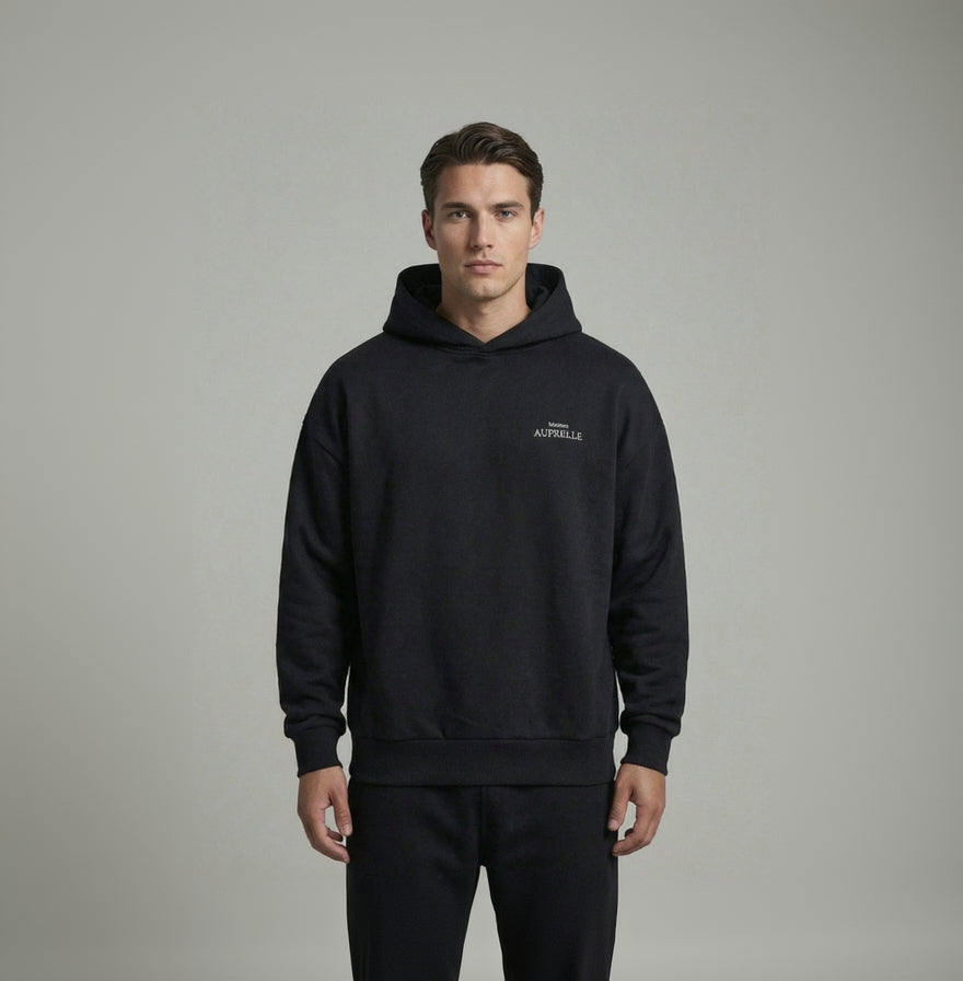 Man wearing a black hoodie with brand logo on a gray background